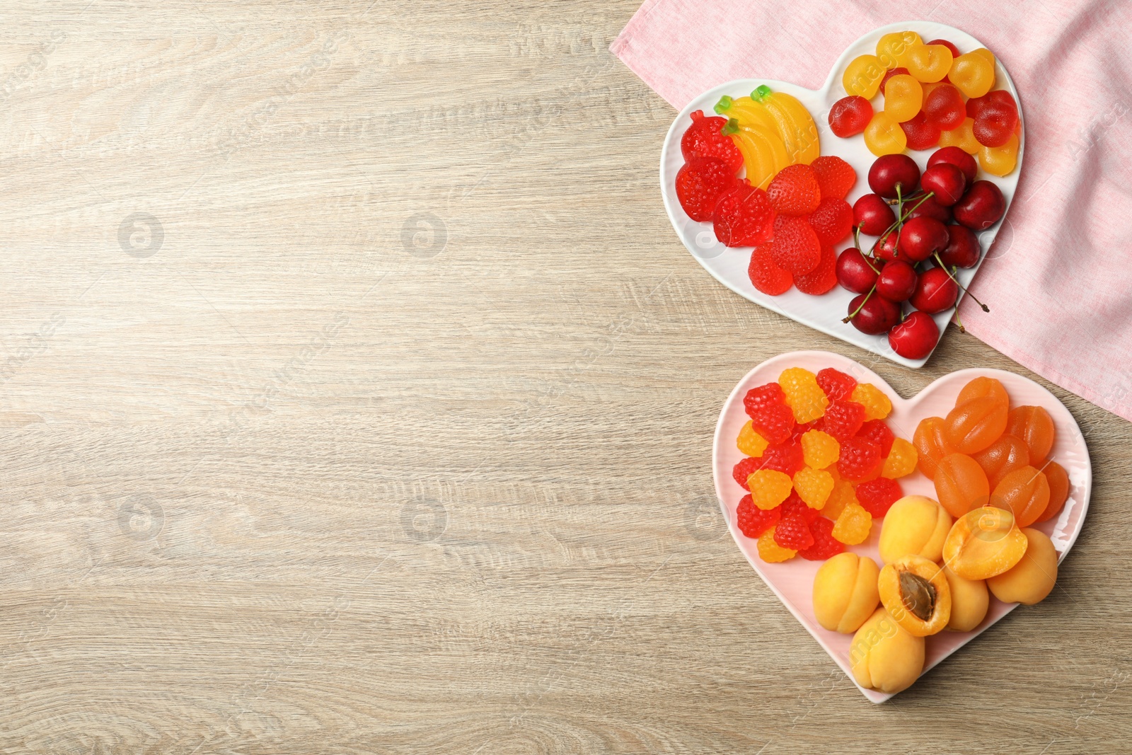 Photo of Delicious gummy candies and fresh fruits on wooden table, flat lay. Space for text