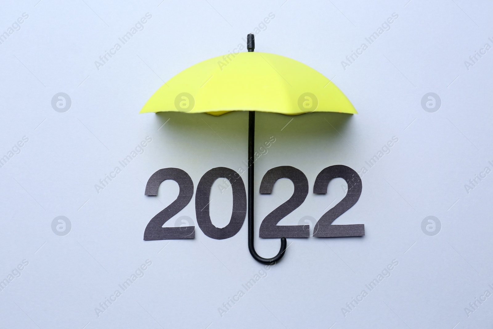Photo of Mini umbrella and number 2022 on white background, top view