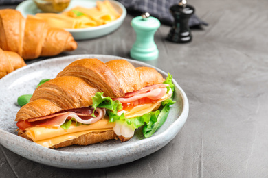 Photo of Tasty croissant sandwich with ham and cheese on grey table