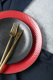 Elegant ceramic plates and cutlery on light textured table, flat lay