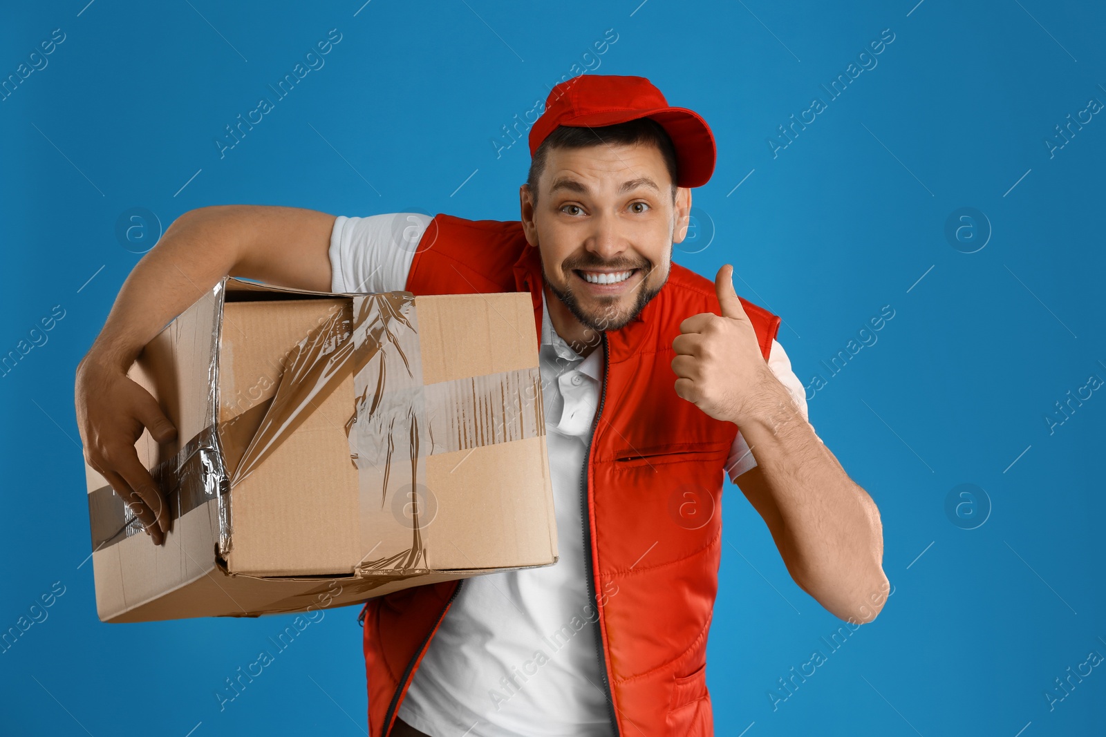 Photo of Emotional courier with damaged cardboard box on blue background. Poor quality delivery service