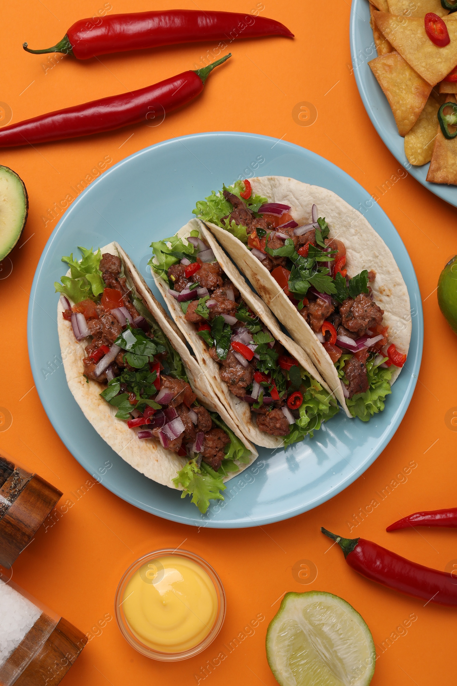 Photo of Flat lay composition with delicious tacos on orange table