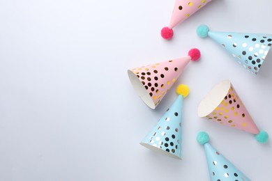 Photo of Beautiful party hats with pompoms on light background, top view. Space for text