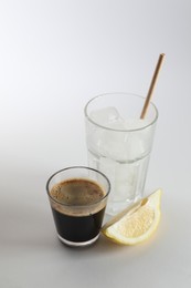 Photo of Coffee and ice cubes in different glasses, cut lemon on white background