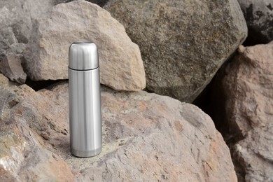 Photo of Metallic thermos with hot drink on stone outdoors, space for text