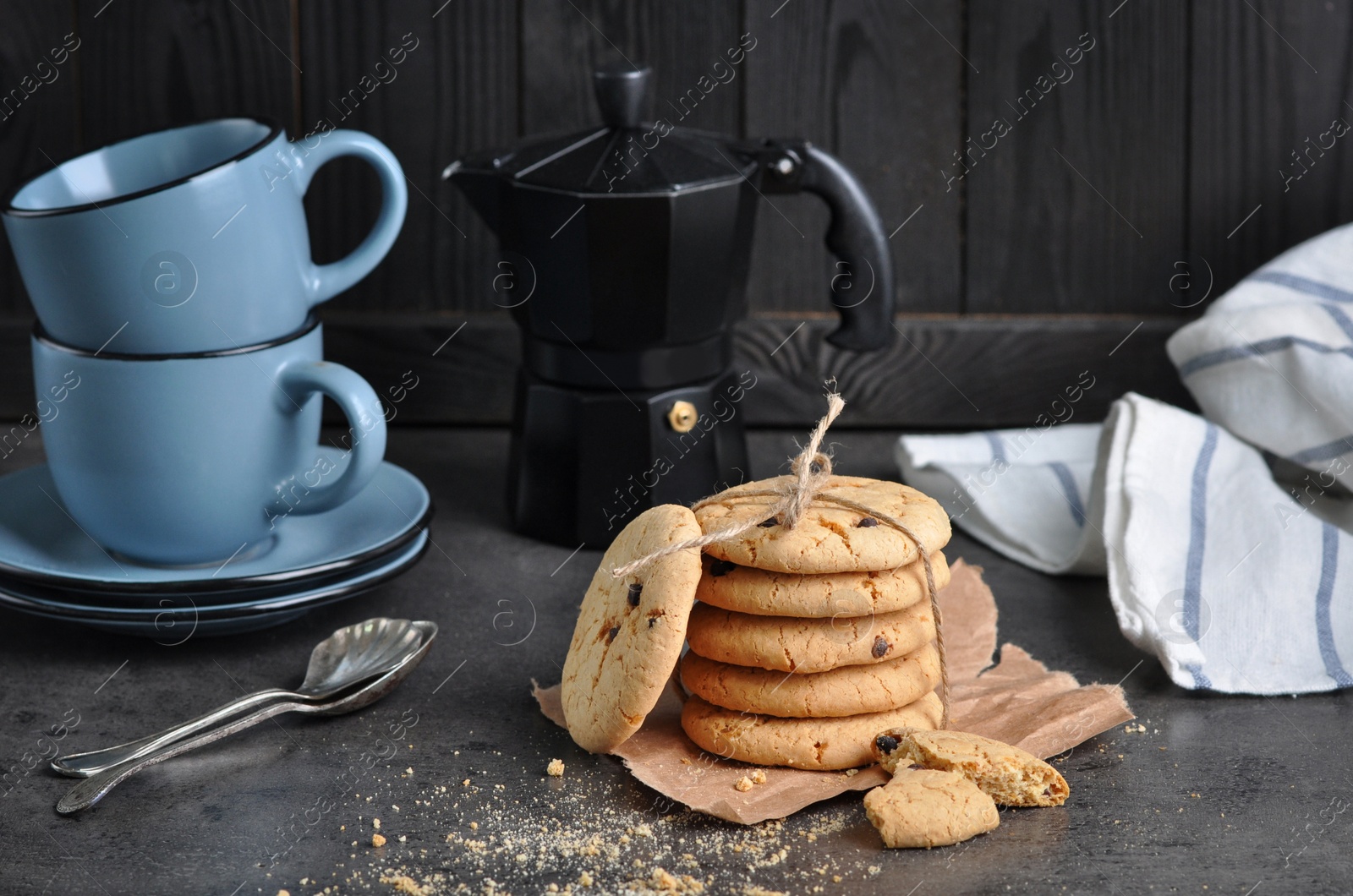 Photo of Tasty homemade cookies tied with rope near cups on grey table