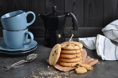 Photo of Tasty homemade cookies tied with rope near cups on grey table