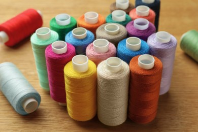 Photo of Many colorful sewing threads on wooden table