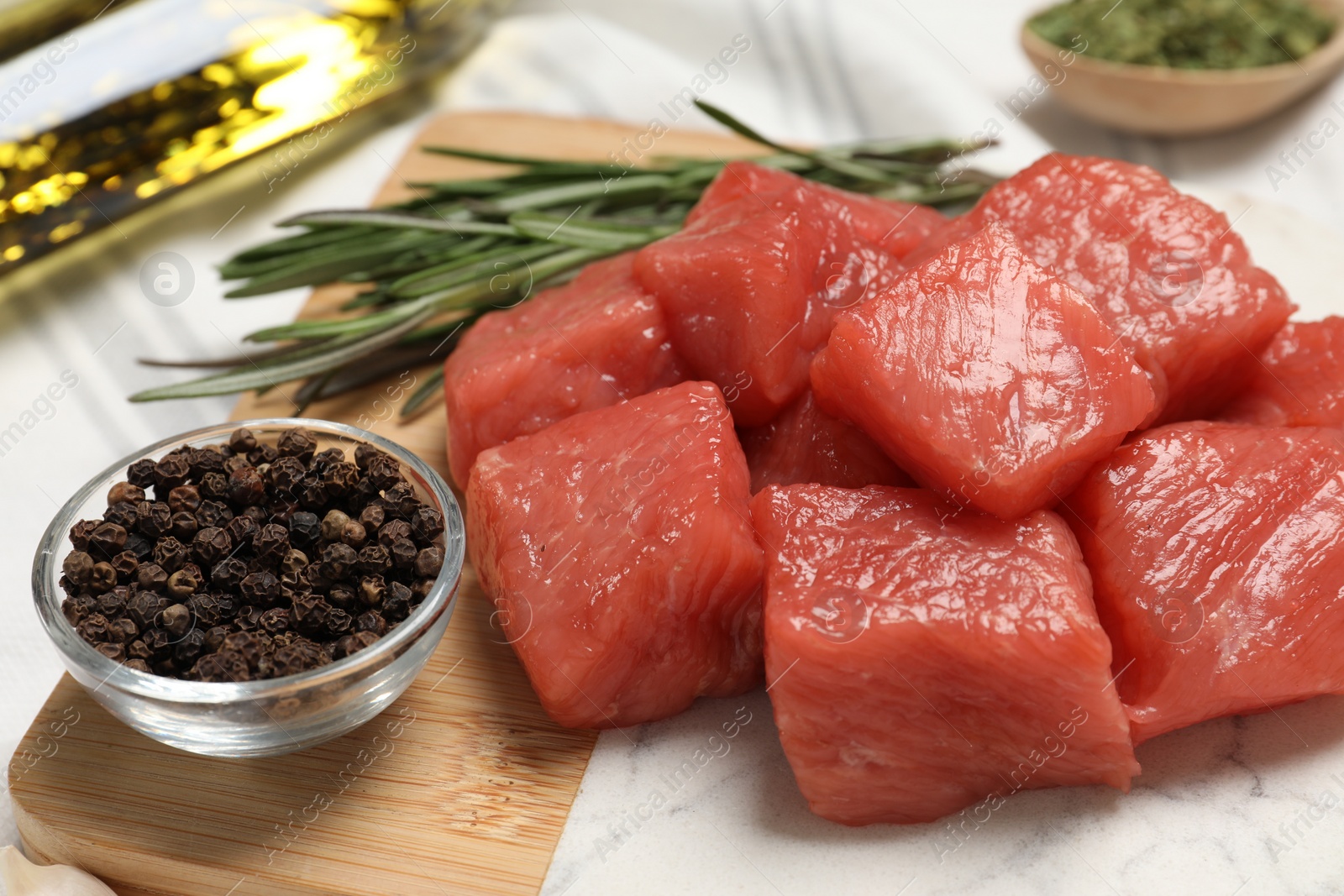 Photo of Cooking delicious goulash. Raw beef meat with rosemary and spices on board, closeup