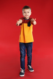 Photo of Little boy showing thumbs up on red background