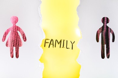 Divorce concept. Balloon with word Family between man and woman silhouettes, view through holes in white paper
