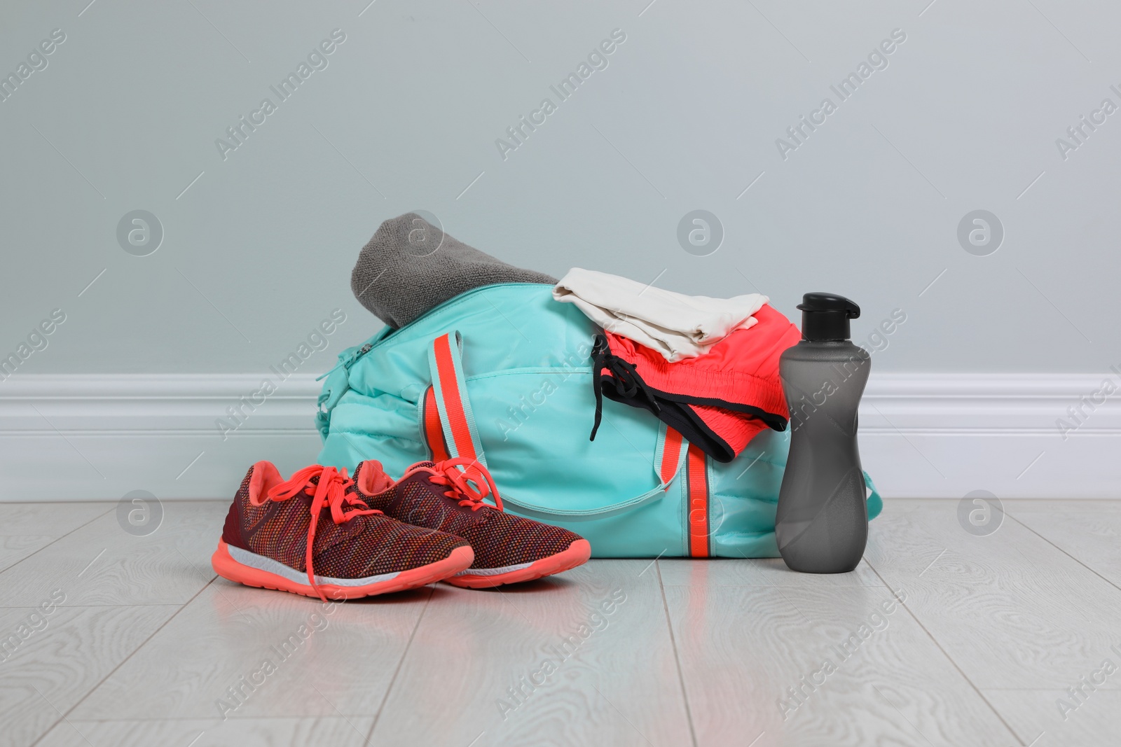 Photo of Bag with different sports equipment on wooden floor indoors