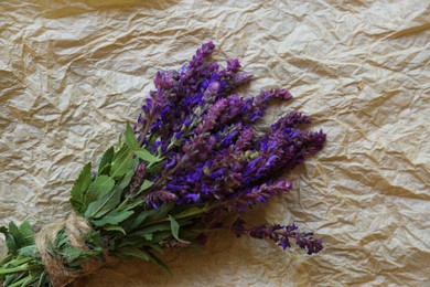 Photo of Bunch of beautiful salvia on parchment, top view