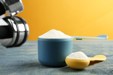 Photo of Measuring scoops of protein powder on blue wooden table