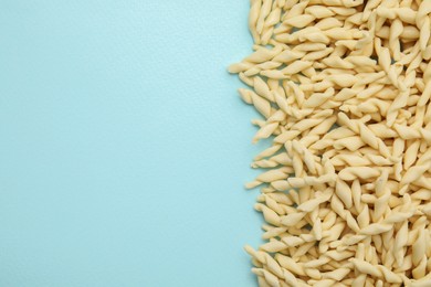 Photo of Uncooked trofie pasta on light blue background, flat lay. Space for text
