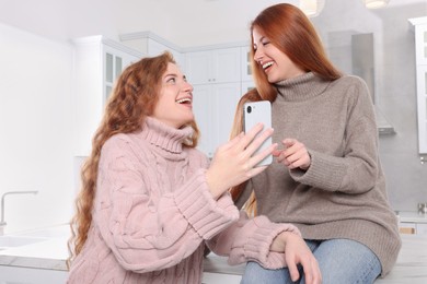 Photo of Beautiful young sisters spending time together in kitchen