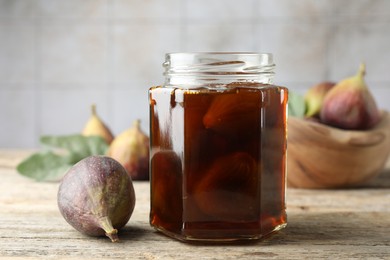 Photo of Jar of tasty sweet jam and fresh figs on wooden table