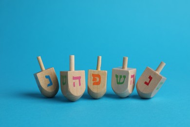 Photo of Wooden dreidels on light blue background. Traditional Hanukkah game