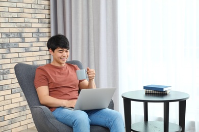 Photo of Man in casual clothes with laptop in living room