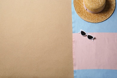 Photo of Straw hat, sunglasses, blanket and space for text on beach sand, top view. Summer vacation