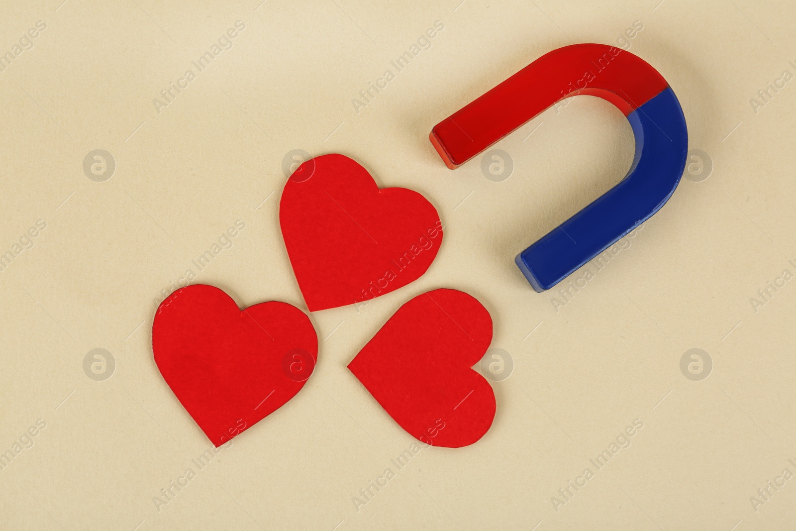 Photo of Magnet and red hearts on beige background, flat lay