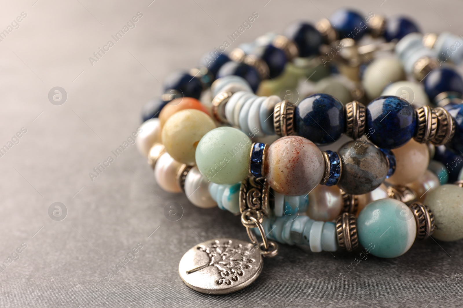 Photo of Beautiful bracelets with gemstones on grey background, closeup. Space for text