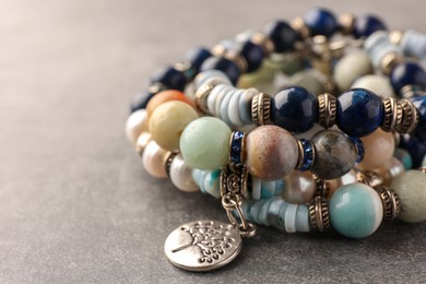 Photo of Beautiful bracelets with gemstones on grey background, closeup. Space for text