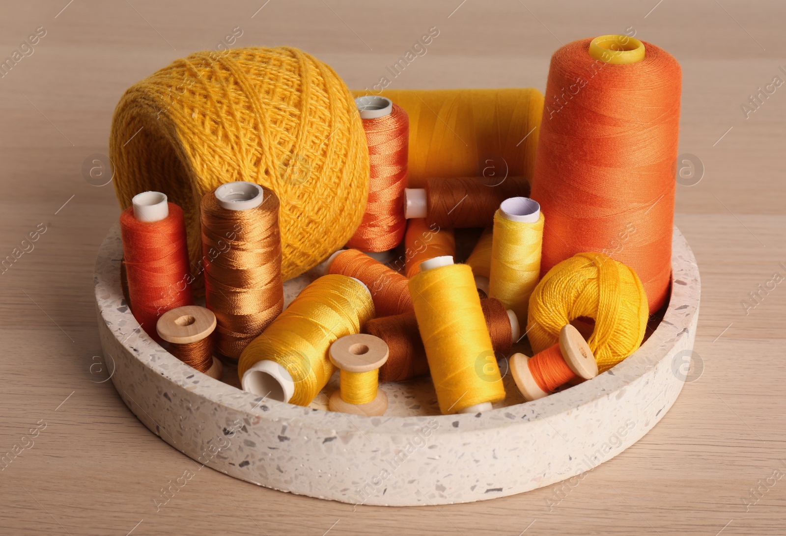 Photo of Color sewing threads in tray on wooden table