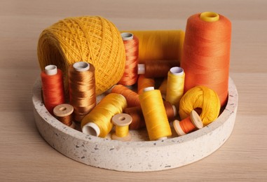 Photo of Color sewing threads in tray on wooden table