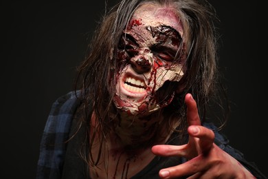 Photo of Scary zombie on dark background, closeup. Halloween monster