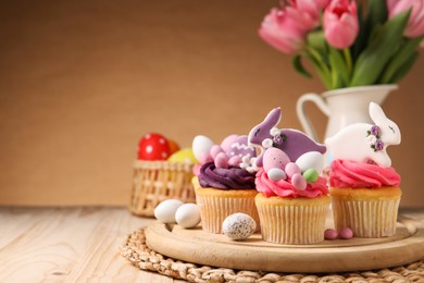 Photo of Tasty cupcakes with Easter decor on wooden table, space for text