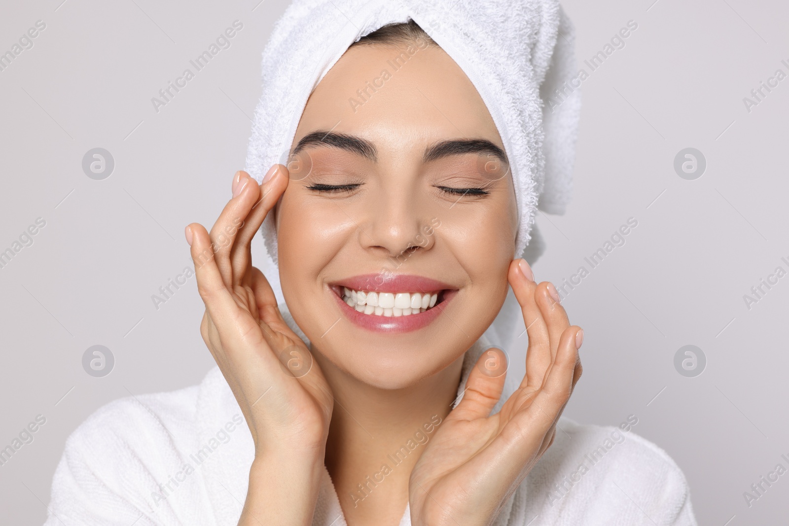 Photo of Young woman in bathrobe with towel on light grey background. Spa treatment