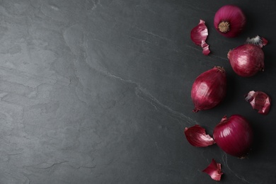 Ripe red onion bulbs on black table, flat lay. Space for text