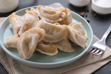 Photo of Delicious dumplings (varenyky) with potatoes and onion served on black table, closeup