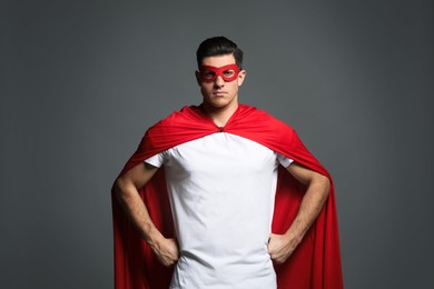 Photo of Man wearing superhero cape and mask on grey background