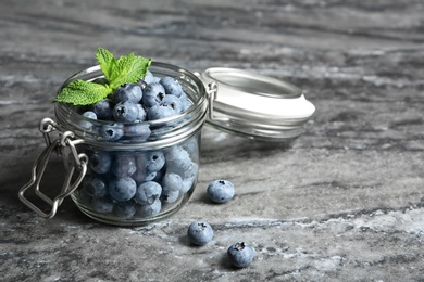 Photo of Jar with juicy and fresh blueberries on color table. Space for text