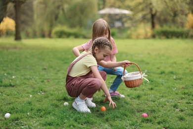 Photo of Easter celebration. Cute little girls hunting eggs outdoors