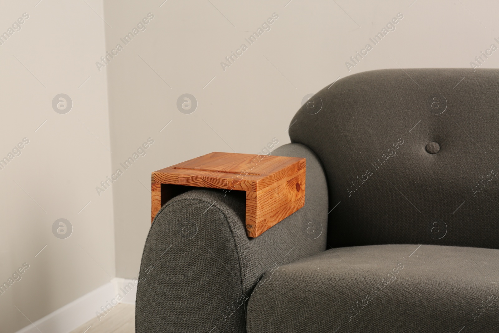 Photo of Wooden armrest table on sofa in room. Interior element