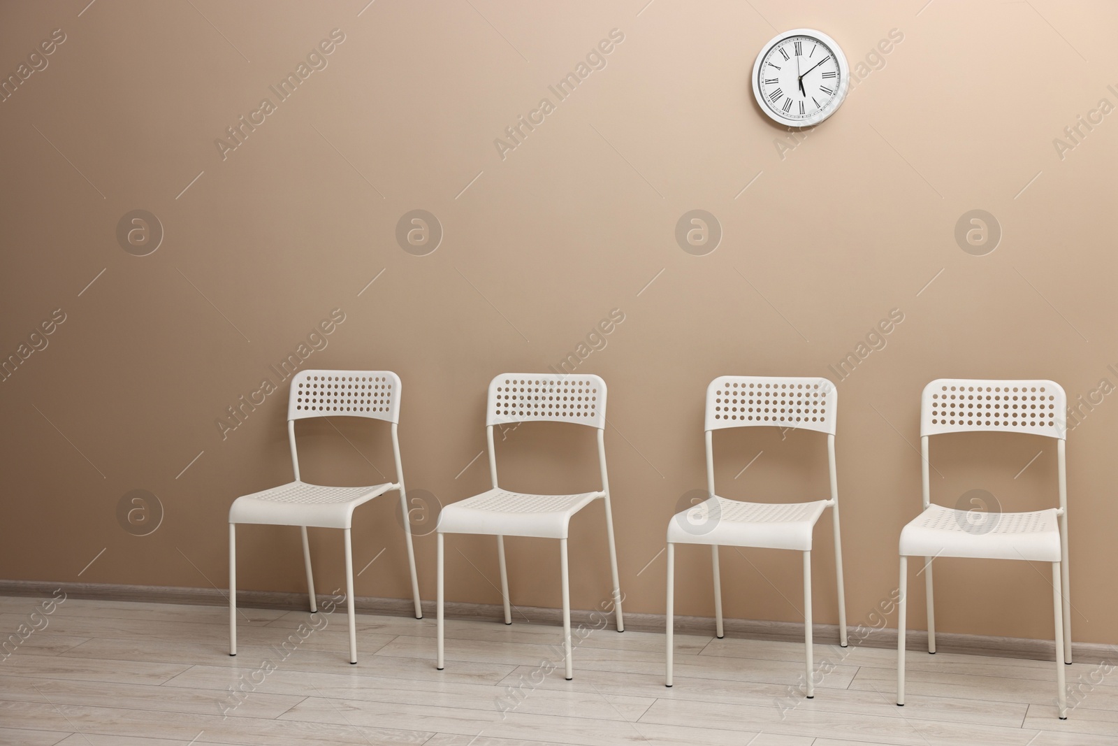 Photo of Many chairs near beige wall in waiting area indoors