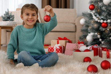 Photo of Cute little girl with Christmas balls at home