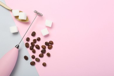 Pink milk frother wand, coffee beans and sugar cubes on color background, flat lay. Space for text