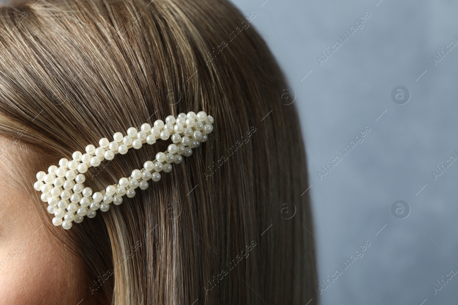 Photo of Young woman with beautiful hair clip on blue background, closeup