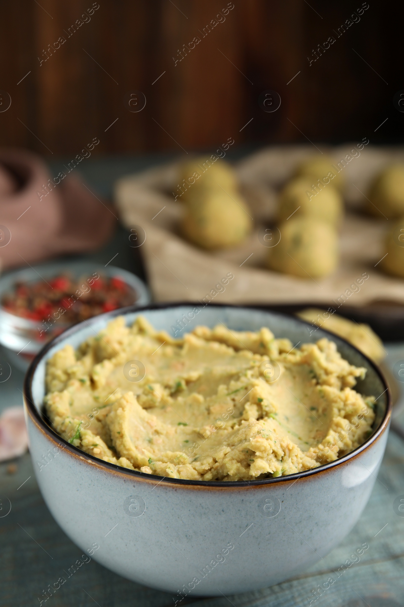 Photo of Bowl of chickpea puree on blue wooden table, space for text. Falafel recipe