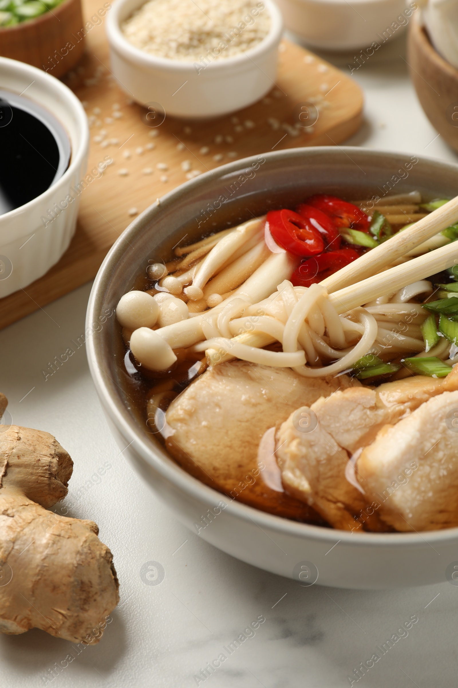 Photo of Delicious ramen with meat and ingredients on white marble table. Noodle soup