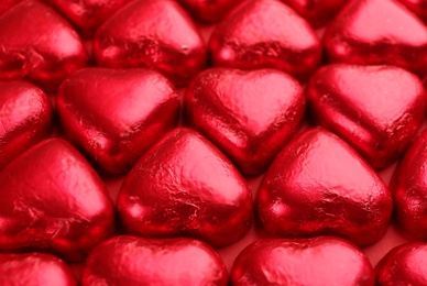 Photo of Heart shaped chocolate candies on red background, closeup