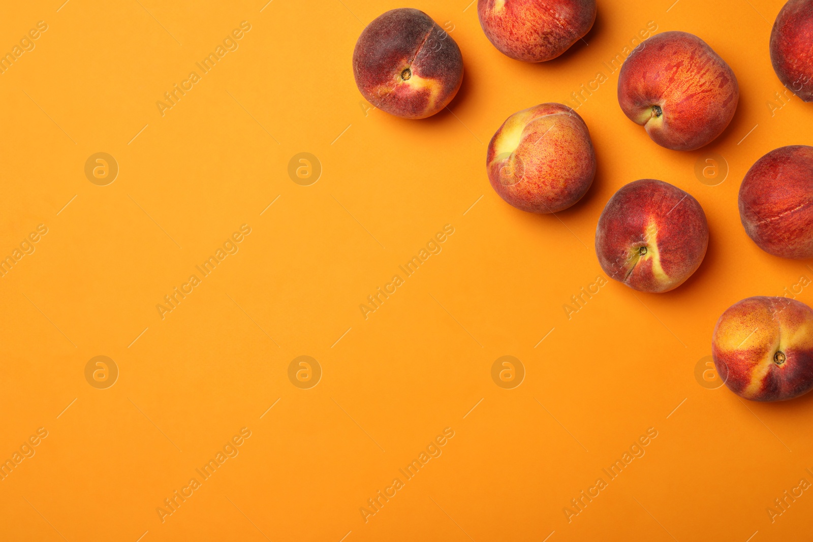 Photo of Flat lay composition with ripe peaches on orange background, space for text