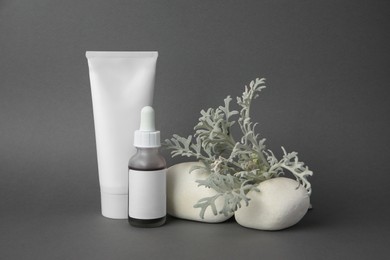 Photo of Cosmetic products, stones and silver leaves on dark grey background