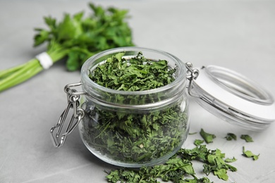 Glass jar with dried parsley on grey stone table