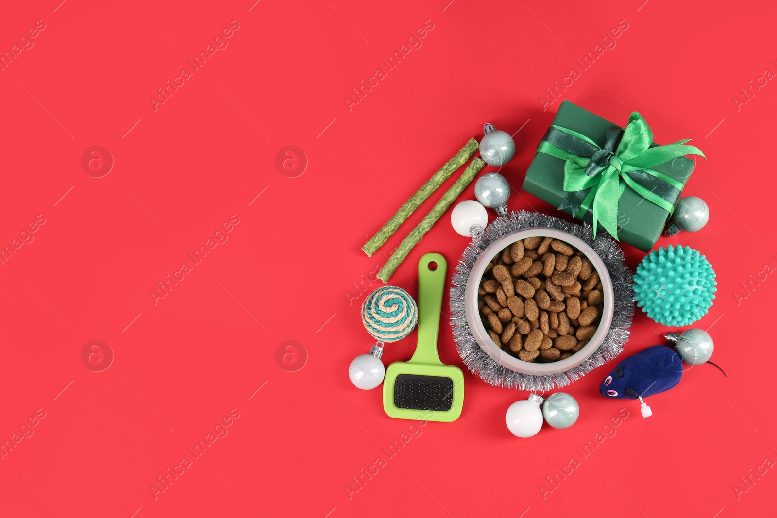 Photo of Different pet goods with Christmas gift on red background, flat lay and space for text. Shop assortment