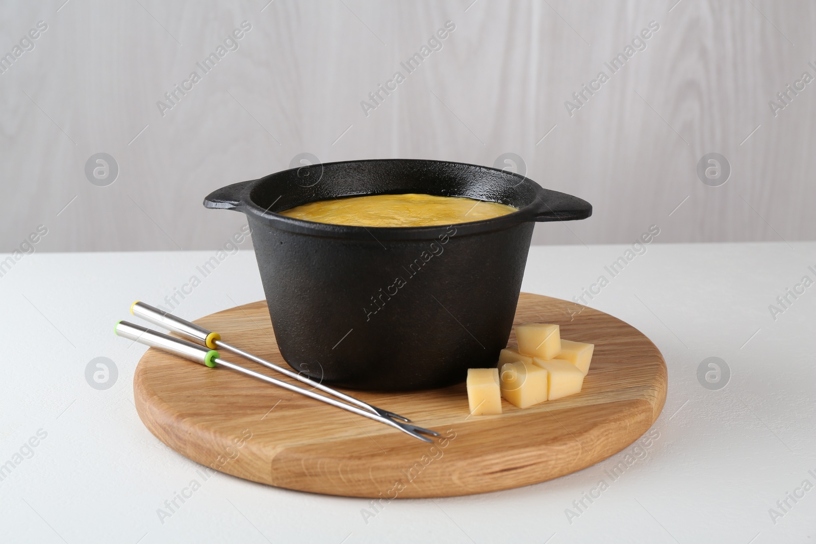 Photo of Fondue with tasty melted cheese and forks on white table